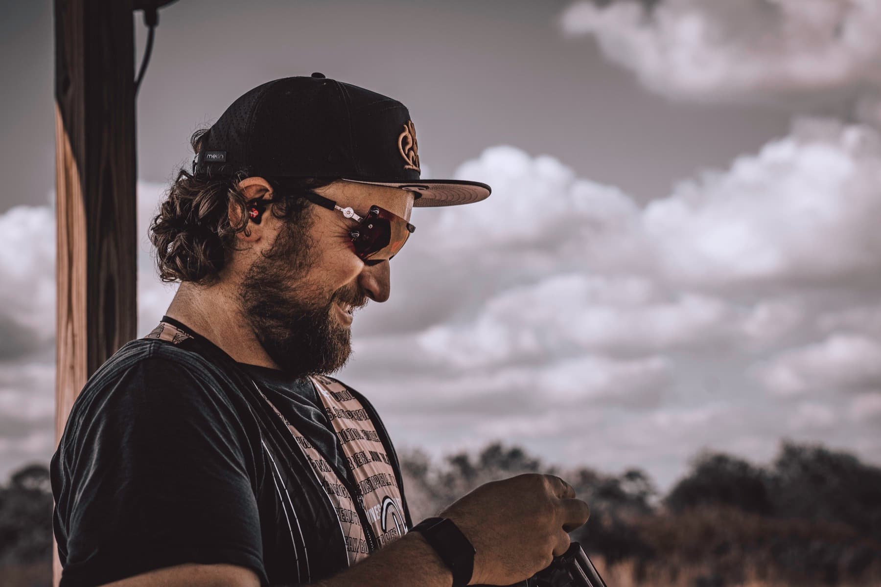 David Radulovich looking down with a soft field and cloudy sky behind him.