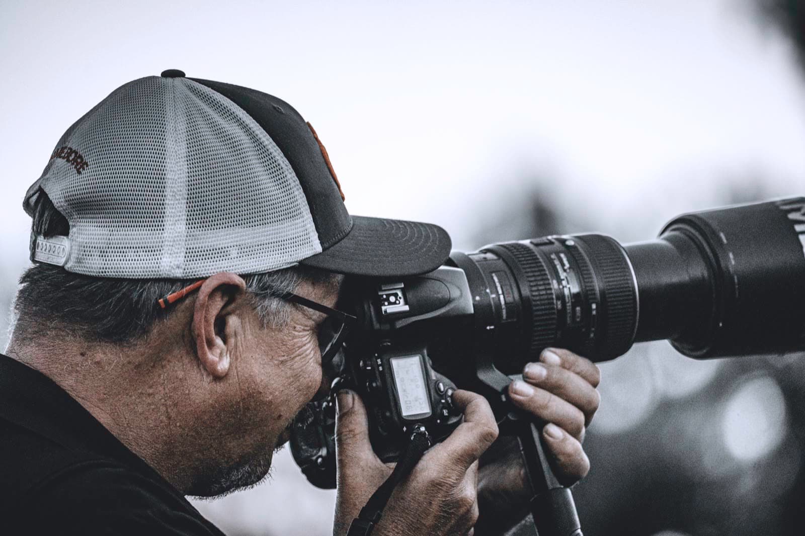 A broadcast photographer looking through a long field lens.