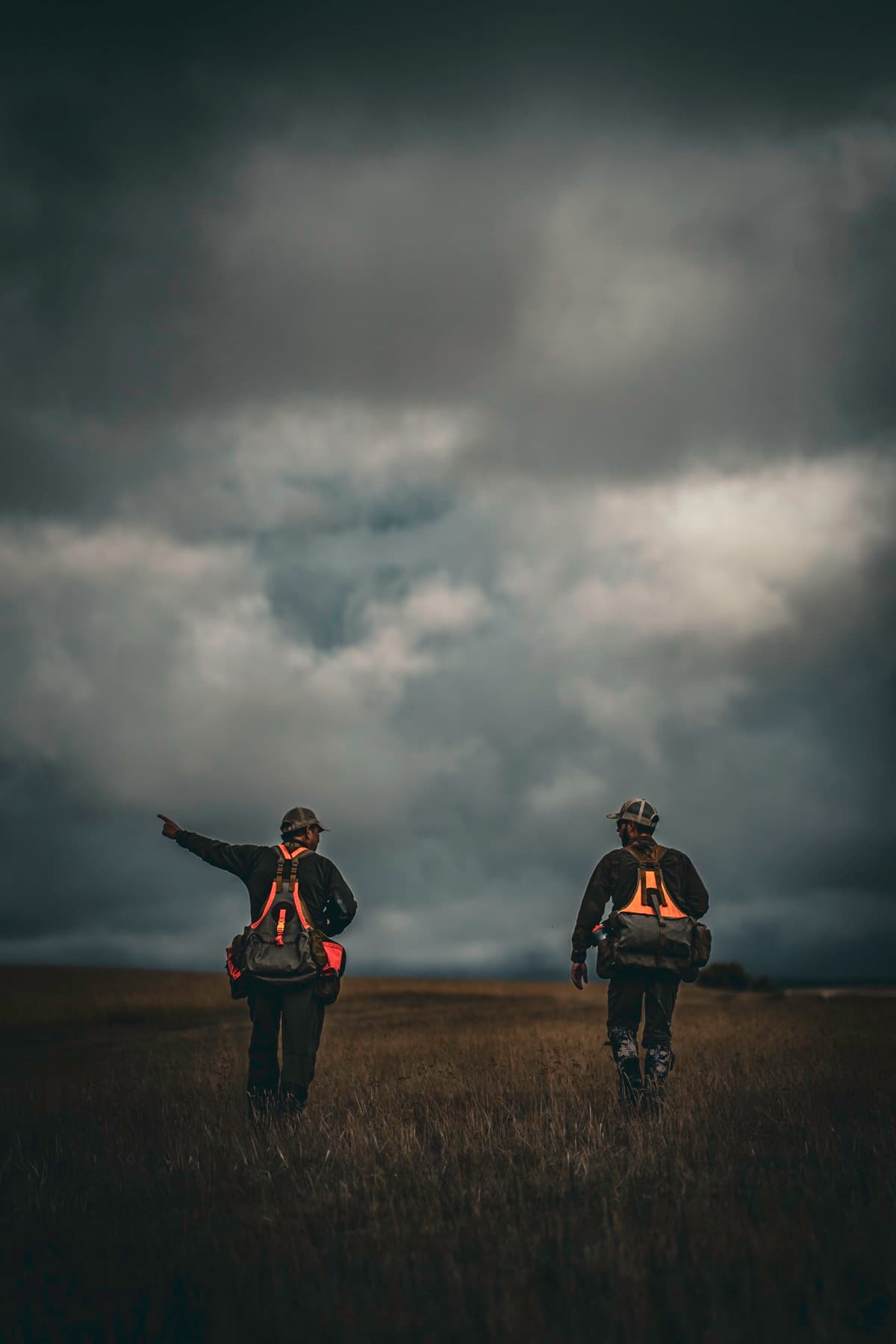 Two people walking through open ground beneath a wide sky.