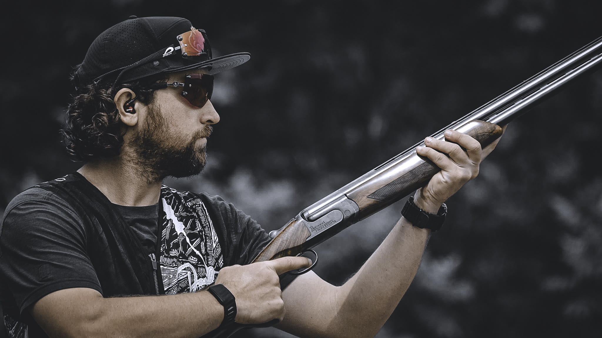 David holding a shotgun in profile against a dark background.